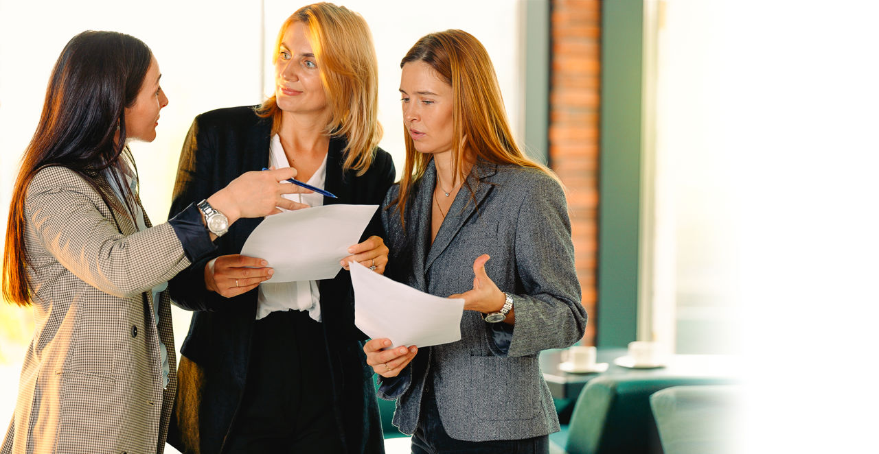 Foto af 3 kvinder stående i en samtalesituation