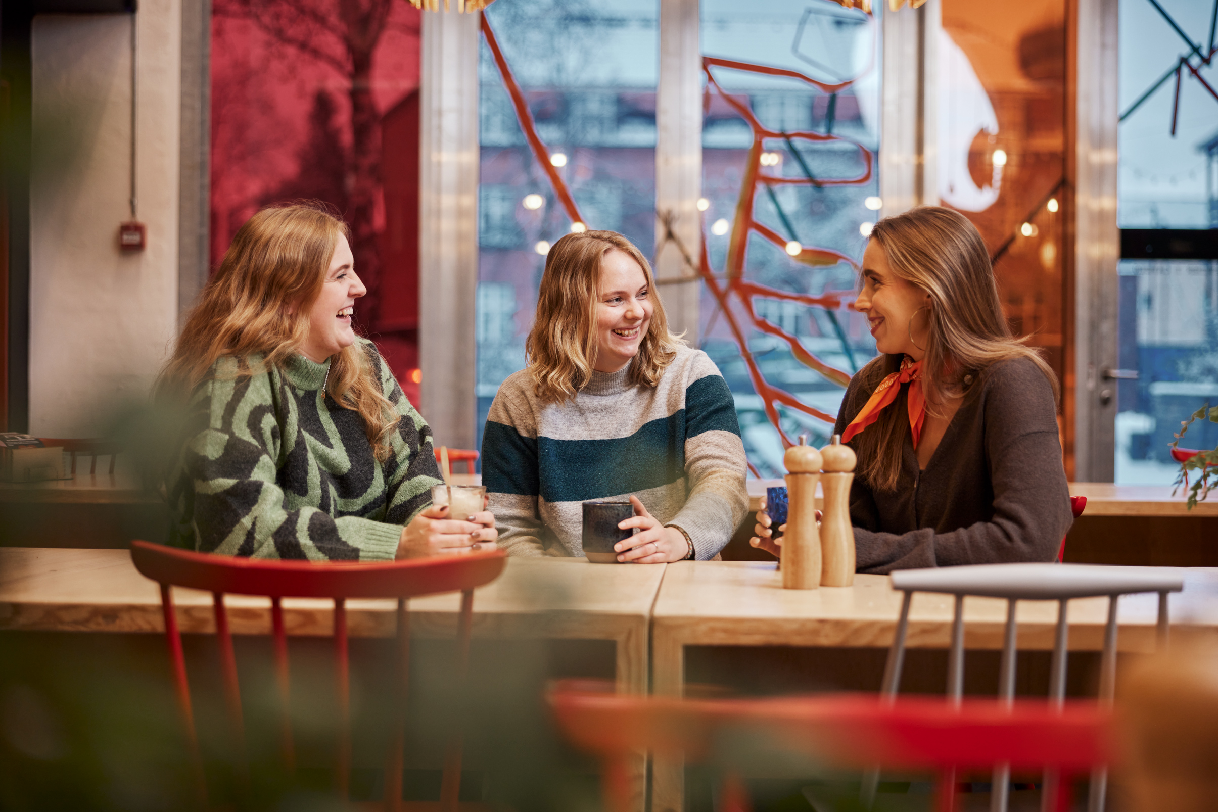 Foto af unge siddende ved et bord med kaffe/the i hænderne