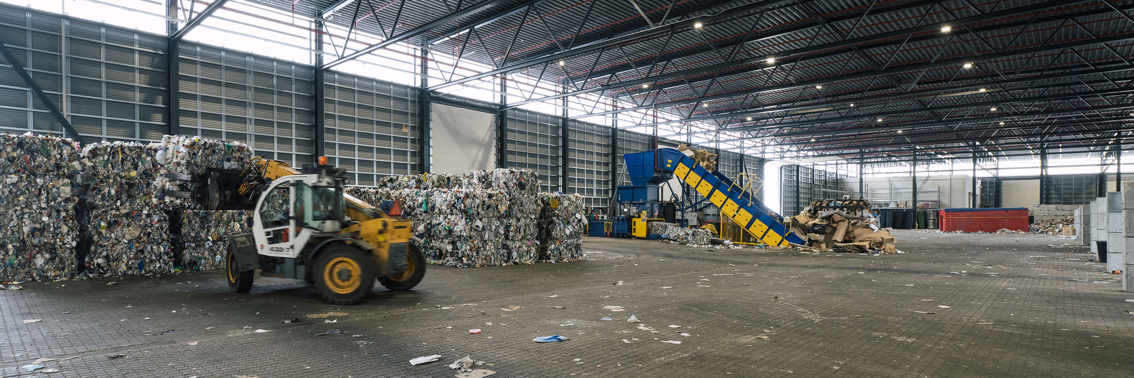Indvendig hal med affaldshåndtering på RessourceCenter Vejle. Stor industrihal med maskiner og affald i forskellige fraktioner.