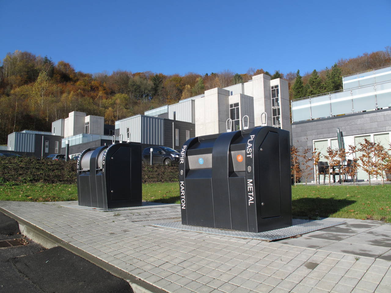 Moderne nedgravede affaldsbeholdere i fællesområde ved nybyggeri i kuperet terræn